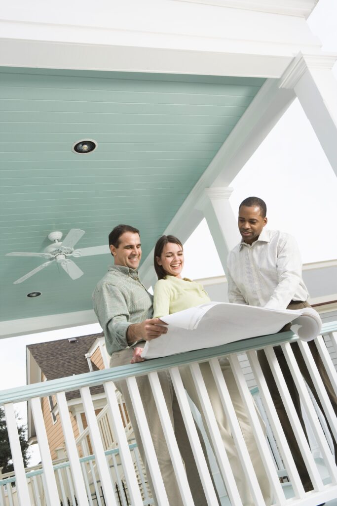 couple and contractor looking at blueprints on porch