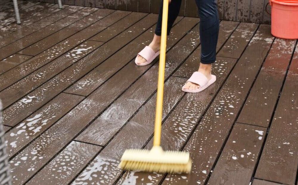 woman using brush on trex deck for cleaning